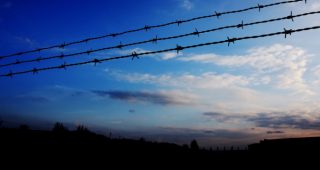Himmel mit Farbverlauf und Stacheldraht im Vordergrund